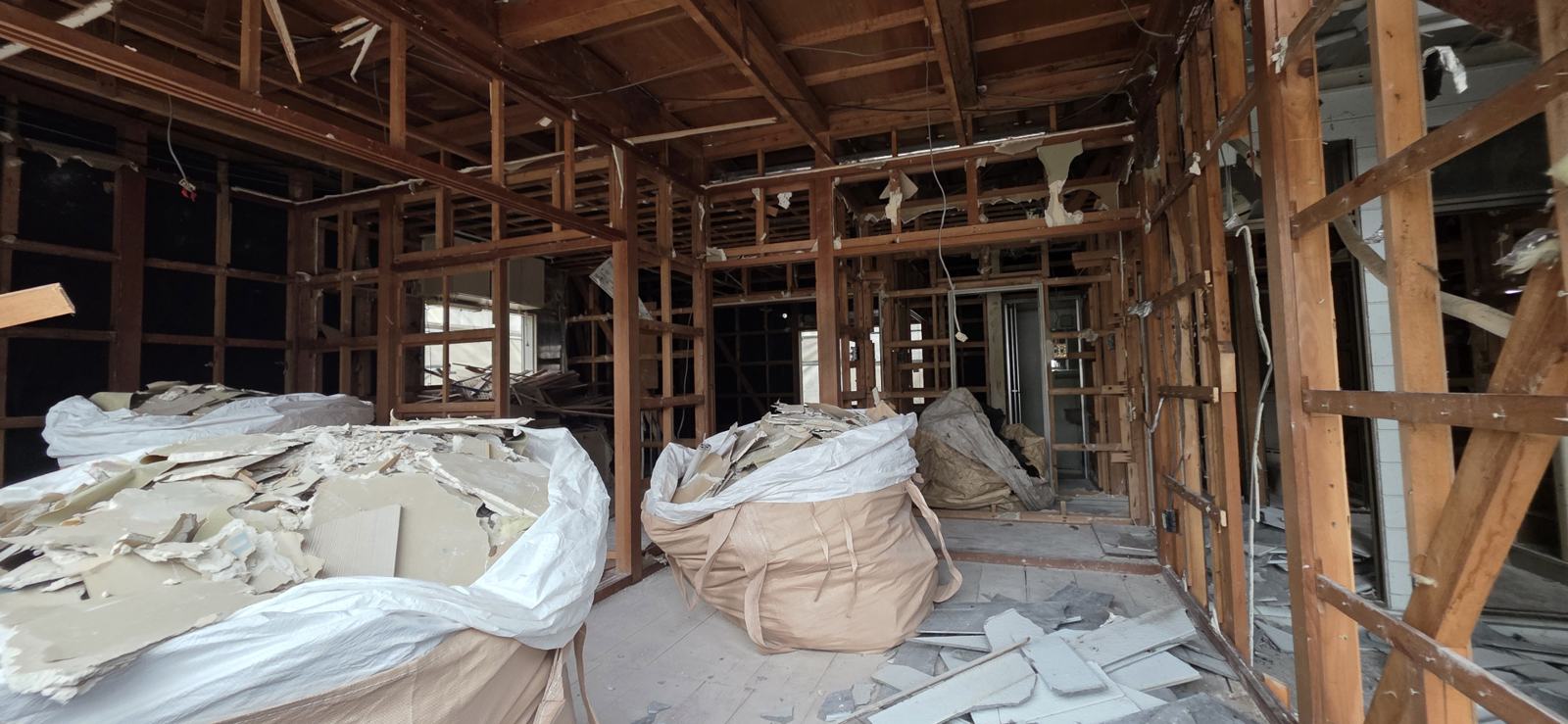解体中の木造住宅と、袋に詰めた廃材